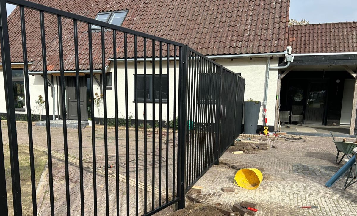 Stalen spijlenhekwerk met poort langs een oprit