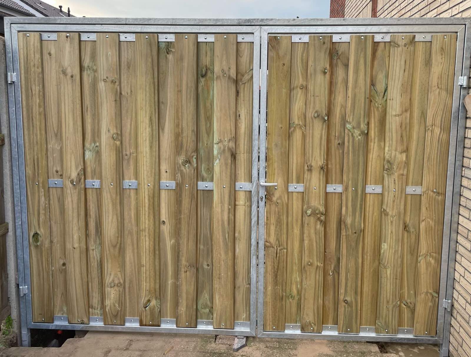 Dubbele stalen poort met verzinkt frame en houten vulling, op maat tussen twee muren