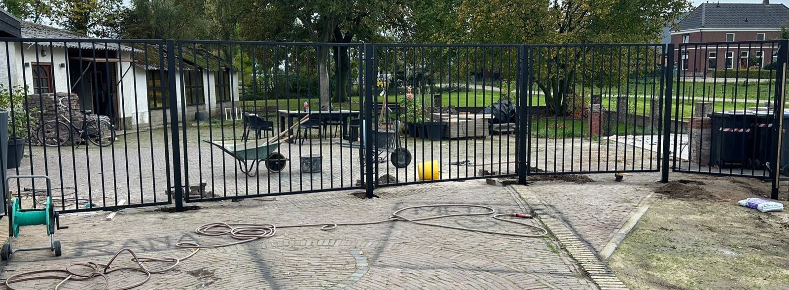 Stalen spijlenhekwerk met dubbele poort langs een erf in Gaanderen